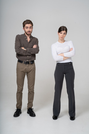 Front view of a young couple in office clothing crossing arms