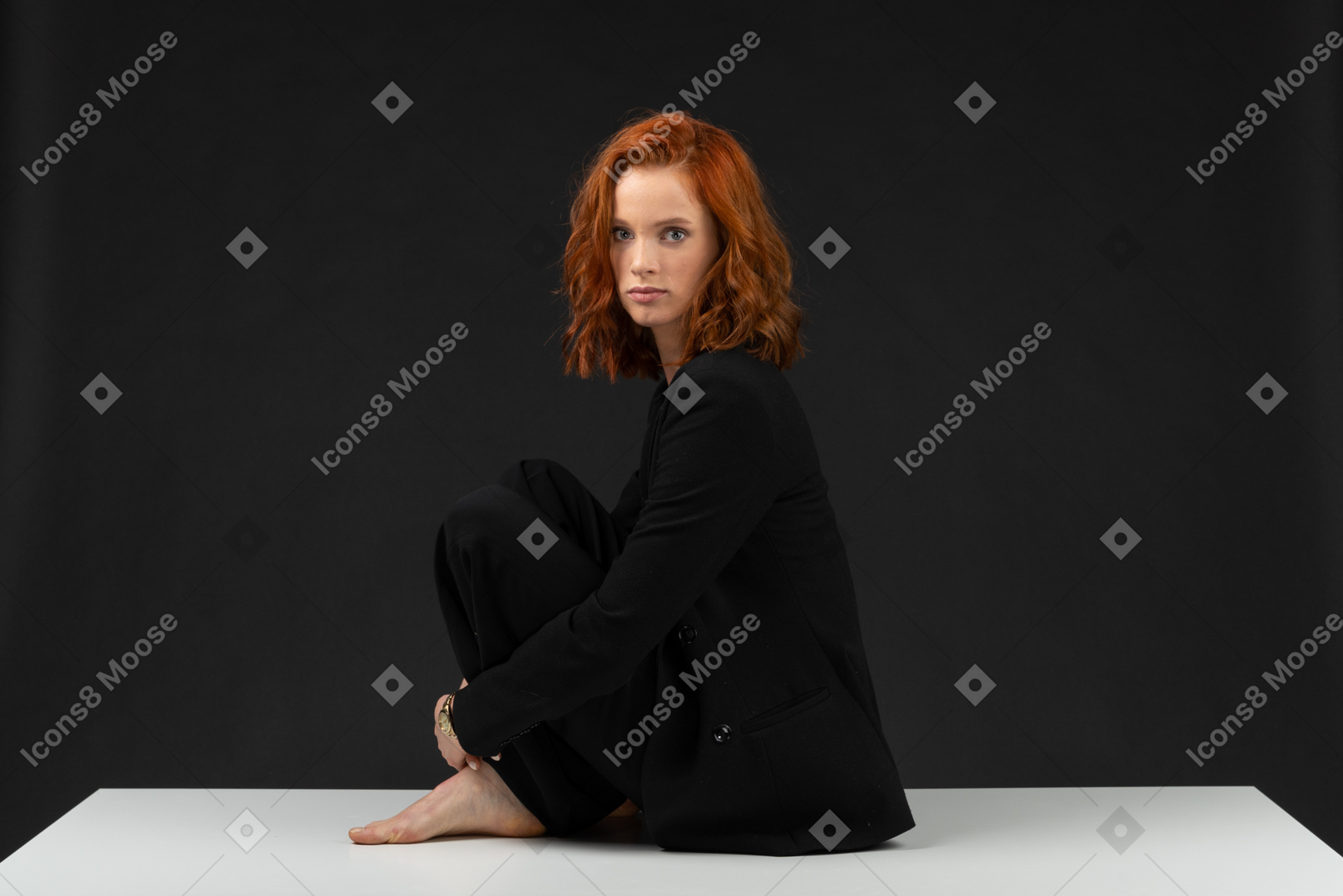 Cute formally dressed girl sitting on the table and looking at the camera