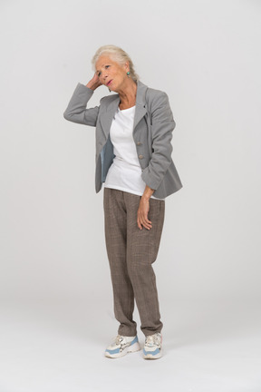 Front view of an old lady in suit touching her hair