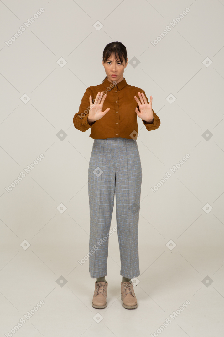 Vista frontal de una joven mujer asiática en calzones y blusa extendiendo sus brazos