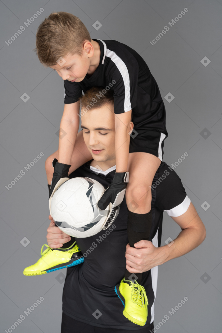 Close-up of a football player holding little boy on his neck