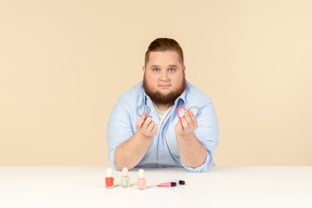 Big man sitting at the table and holding hair bands