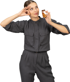 Front view of a young woman in a jumpsuit taking pills out of a jar