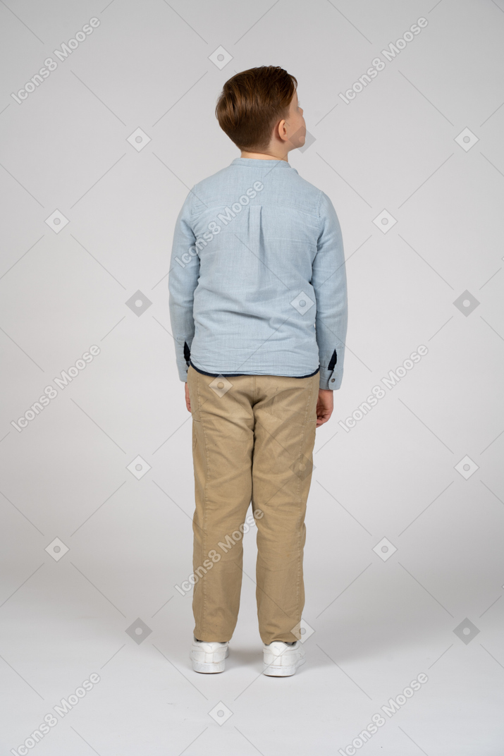 見上げるカジュアルな服装の少年の背面図