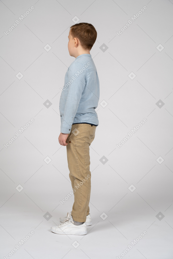 Мальчик в повседневной одежде стоит в профиль