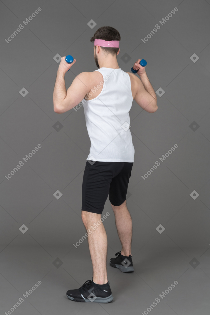 Unrecognizable man lifting blue dumbbells