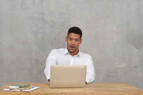 Junger mann, der auf laptop schaut