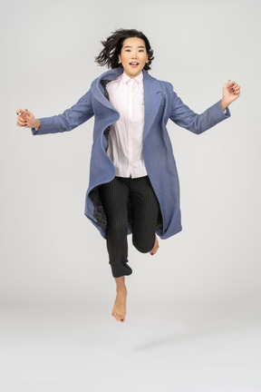 Mujer joven emocionada en abrigo saltando