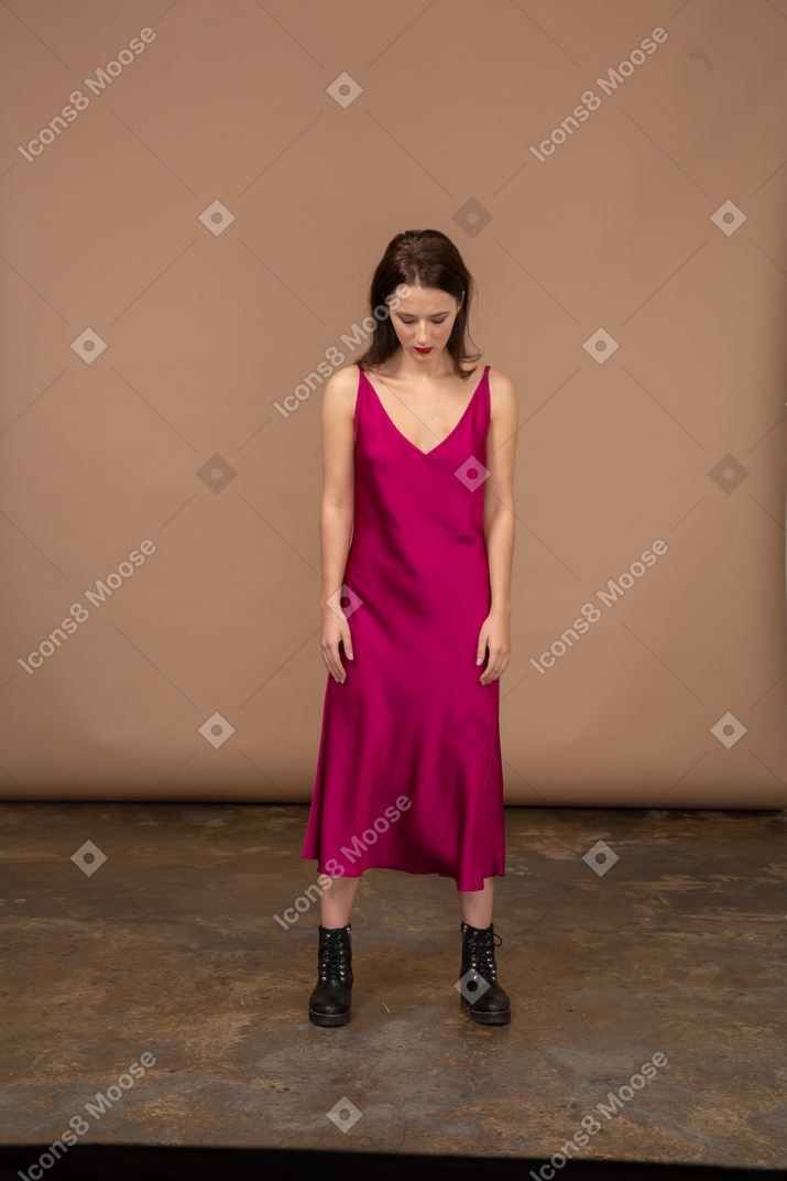 Vista frontal de uma jovem com um lindo vestido vermelho olhando para baixo