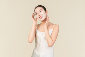 Relaxado jovem mulher asiática com máscara facial tocar a cabeça