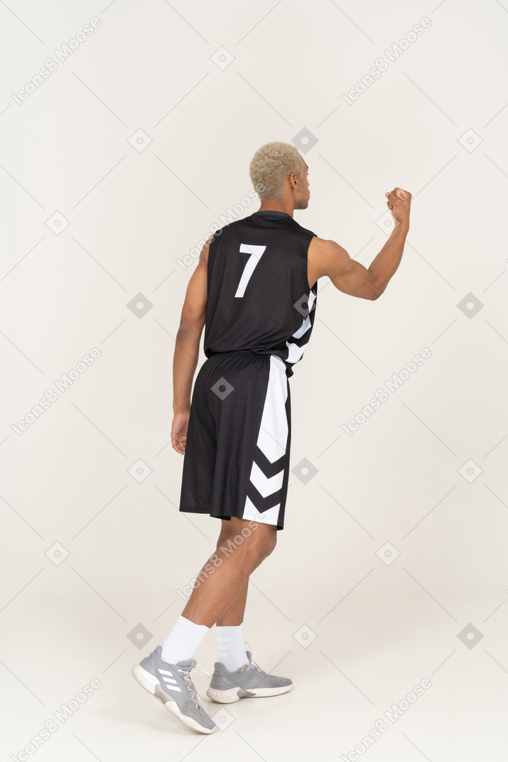 Three-quarter back view of a young male basketball player showing fist