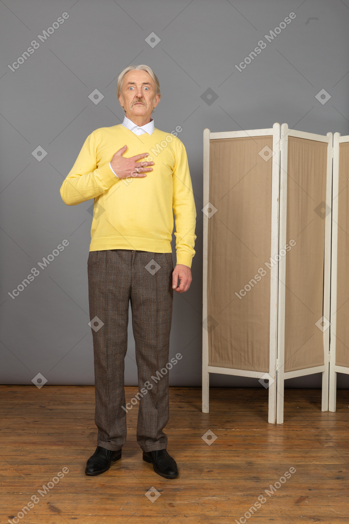 Front view of an astonished old man touching chest