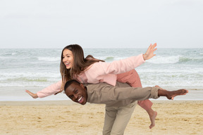 A man carrying a woman on his back on the beach