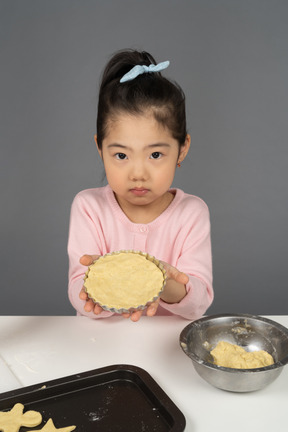 Menina aprendendo a assar biscoitos