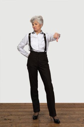 Front view of an old displeased female in office clothes showing a thumb down