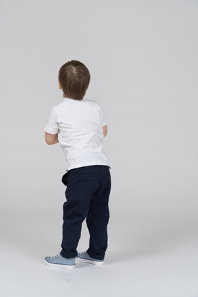 Rear view of little boy standing with arms bent