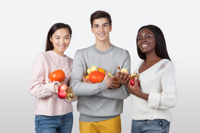 Groupe de gars souriant et tenant des légumes