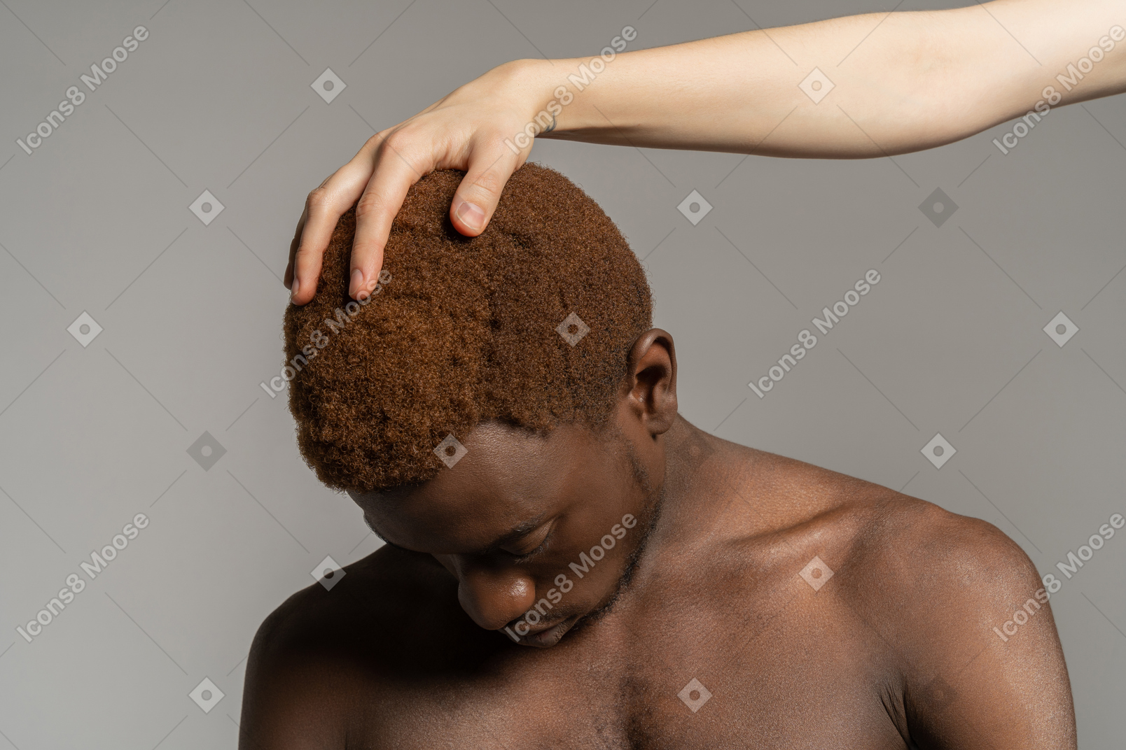 White hand touching hair of a black young man