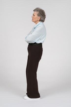 Vista laterale di una donna anziana accigliata con le mani giunte