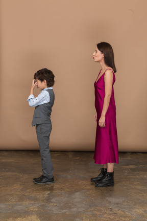 Mujer en vestido rojo y niño en traje gris chaleco de perfil