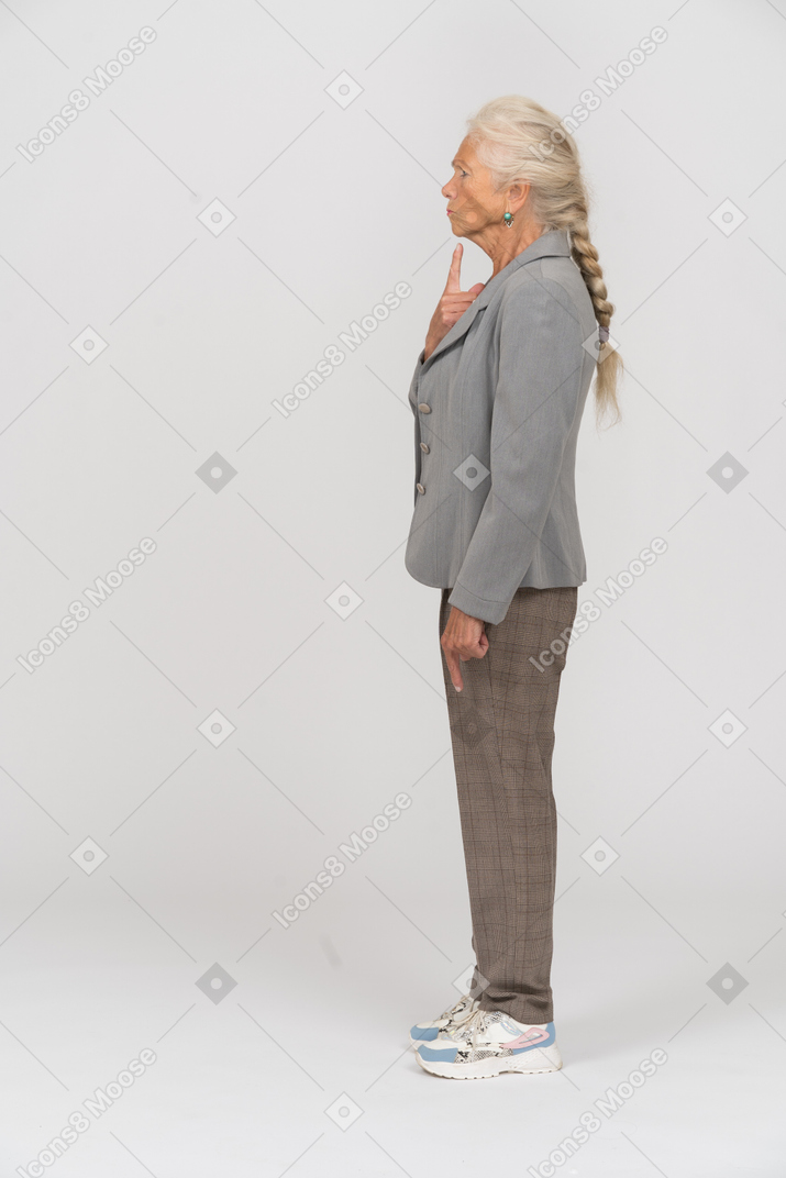 Vista laterale di una vecchia donna in abito che si tocca il mento