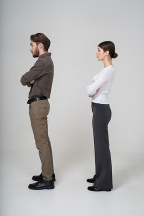 Vue latérale d'un jeune couple en vêtements de bureau traversant les bras