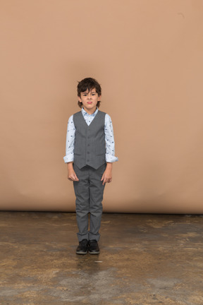 Vista frontal de um menino fofo em um terno cinza parado