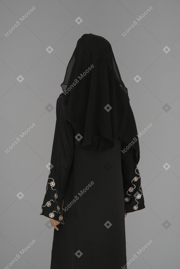 A covered woman standing back to camera