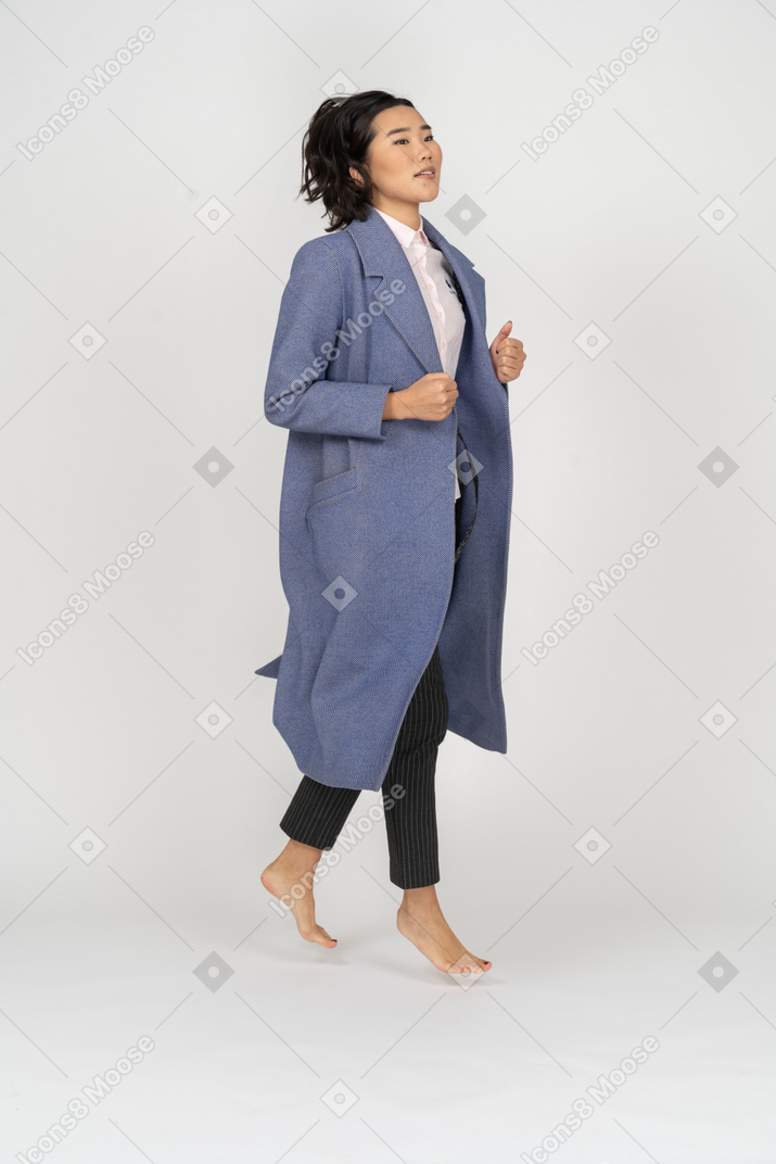 Excited woman in coat mid-air
