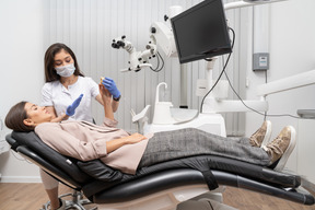 Comprimento total de uma dentista mostrando protótipo de dentes para paciente em um gabinete de hospital