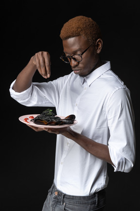 Three-quarters view of a chef preparing his dish for serving