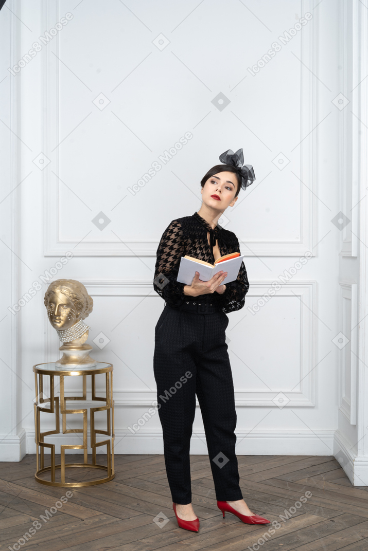 Молодая женщина с книгой в руках смотрит в сторону