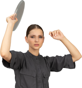 Front view of a young woman in a jumpsuit holding glass plate