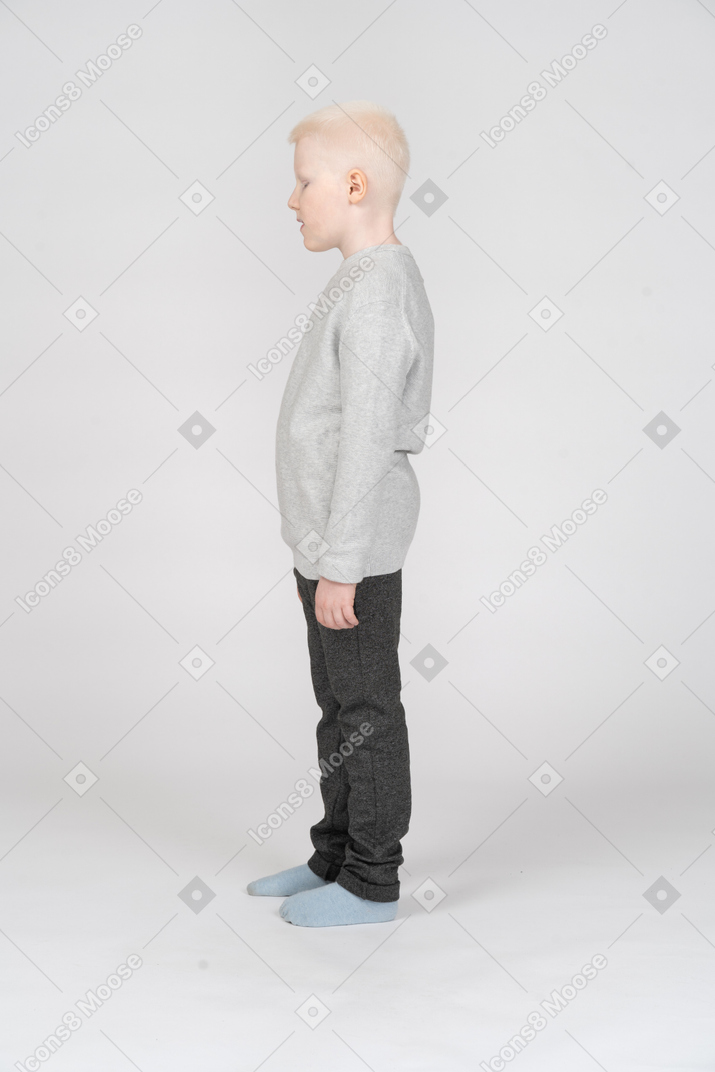 Side view of a kid boy in casual clothes looking down