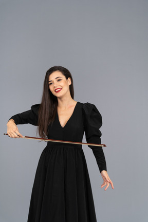 Vista frontale di una giovane donna contenta in abito nero che tiene l'arco