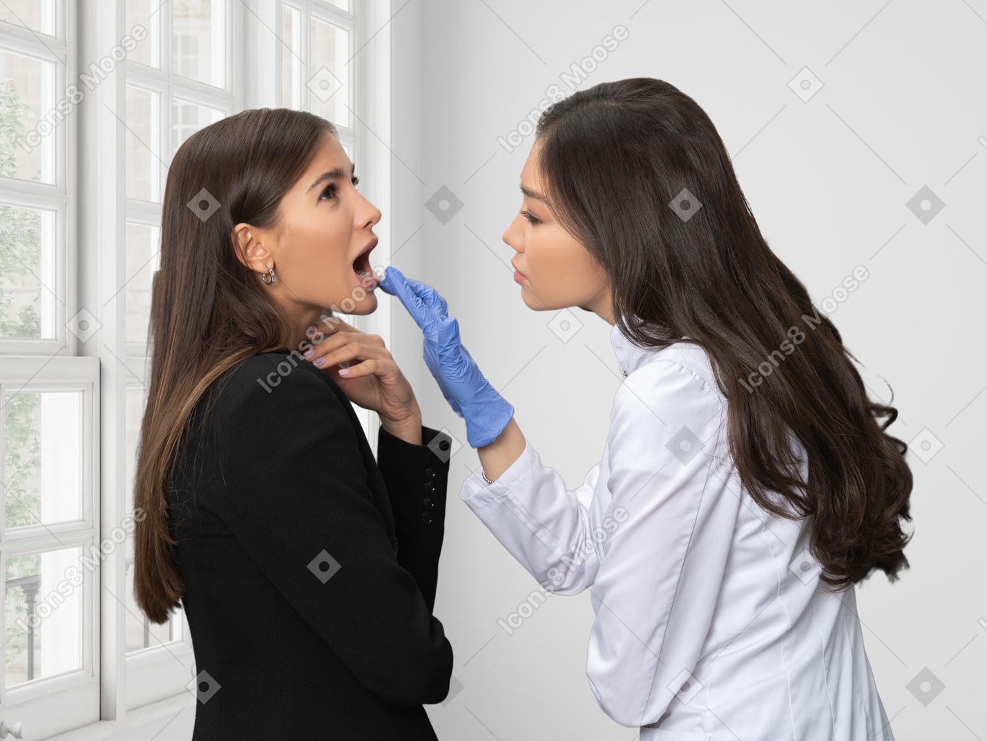 A female patient opening mouth in front of a female dentist