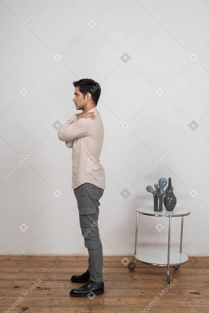 一个穿着休闲服的男人拥抱自己的侧视图