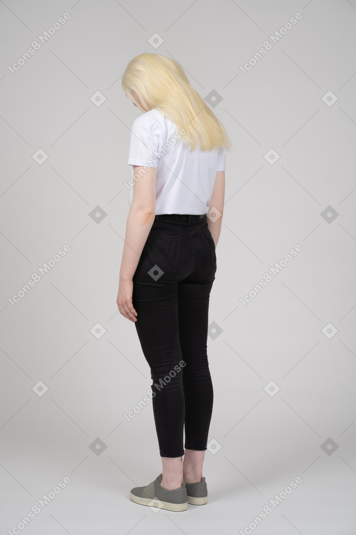 Vista traseira de três quartos de uma adolescente com a cabeça baixa