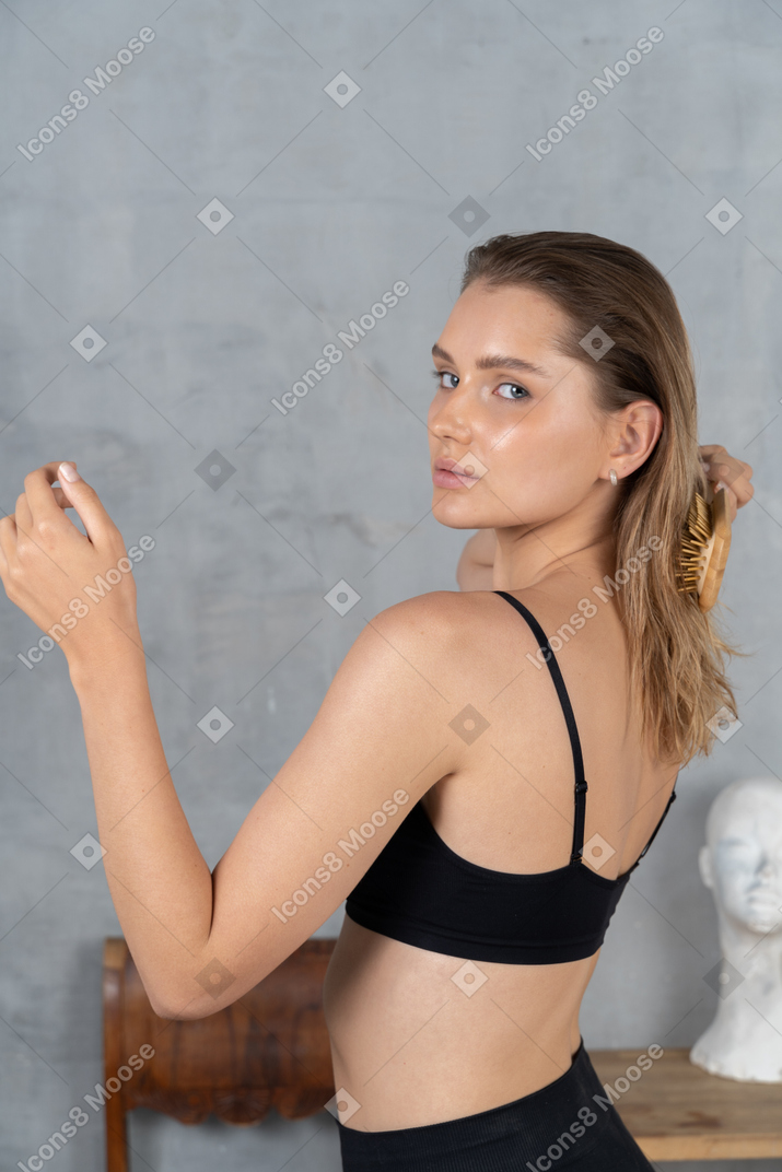 Pretty young woman looking over shoulder while brushing hair