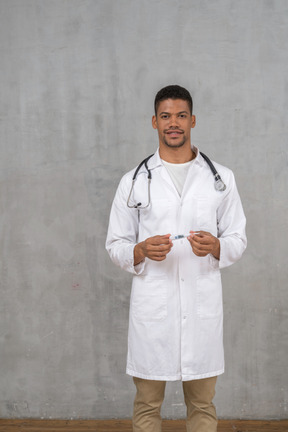 Smiling male doctor holding a thermometer