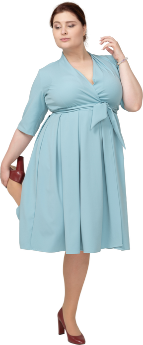 Vue de face d'une femme en robe bleue en équilibre sur une jambe