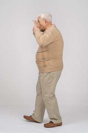 Side view of an old man in casual clothes scaring someone