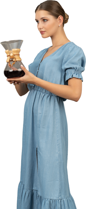 ワインのピッチャーを保持している青いドレスを着た若い女性の4分の3のビュー