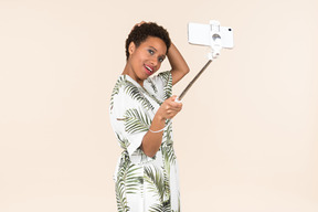 Rire femme afro adulte faisant un selfie avec bâton selfie