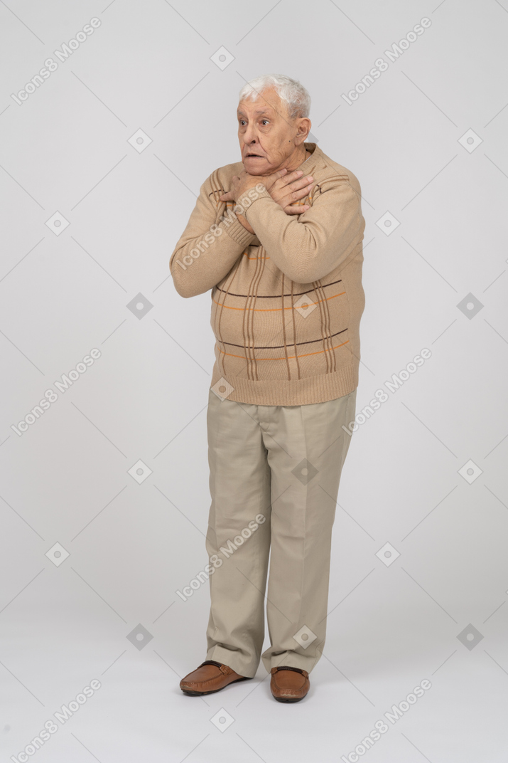 一个穿着休闲服、双手放在肩上站着的害怕老人的正面图