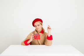 Femme à la mode en manteau et béret tenant une caméra rouge