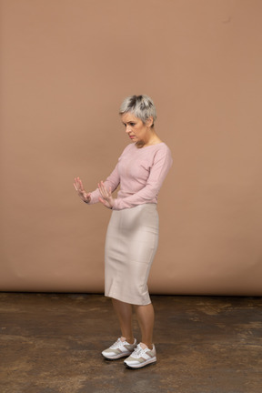 Vista lateral de una mujer en ropa casual mostrando gesto de parada