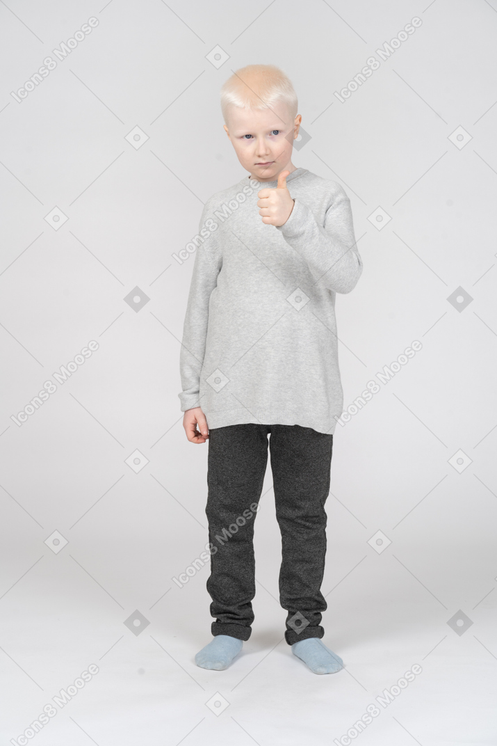 Little boy showing thumb up and looking aside