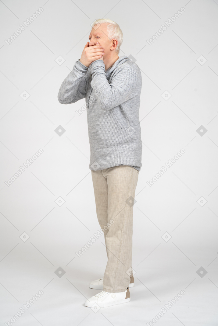 Man in hoodie and trousers covering his mouth
