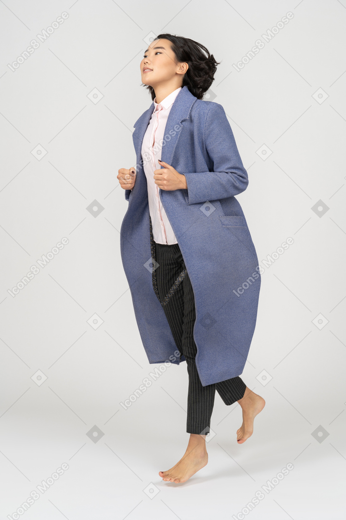 맨발로 달리는 코트를 입은 행복한 여자